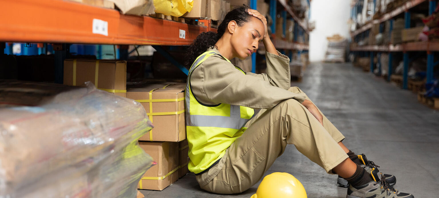 Tired female staff sitting on floor in warehouse. This is a freight transportation and distribution warehouse. Industrial and industrial workers concept